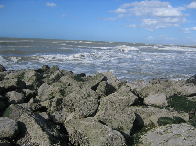 Blick über die Wellenbrecher auf die Flutwellen an der belgischen Nordseeküste